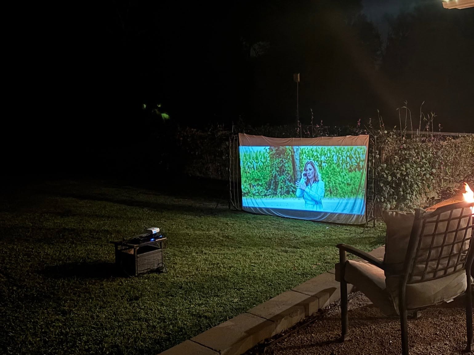 An outdoor movie screen glowing in a Country Place backyard at night